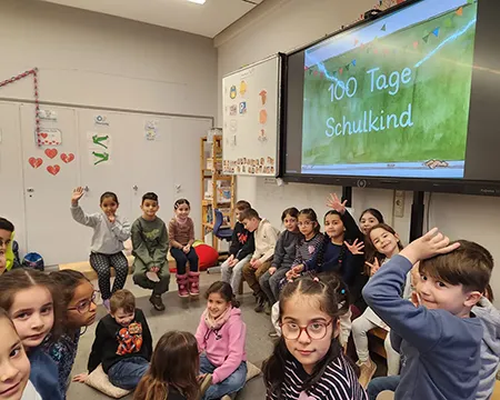 Kinder der Klasse sitzen im Kreis vor der Tafel