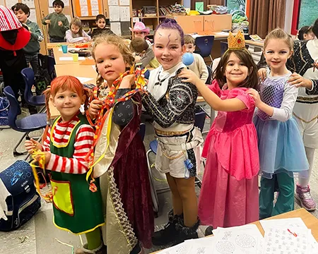 Kinder im Karnevalskostüm machen durch die Klasse eine Polonäse